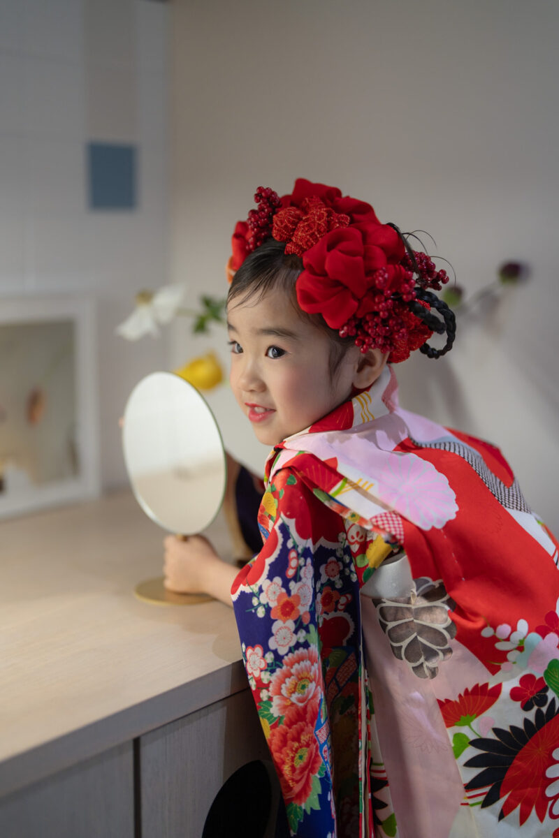 広島市安佐南区・十色写真STUDIOの専用ヘアメイクルームで、着付けとヘアセットを終えた7歳七五三の女の子が手鏡で仕上がりを確認している様子