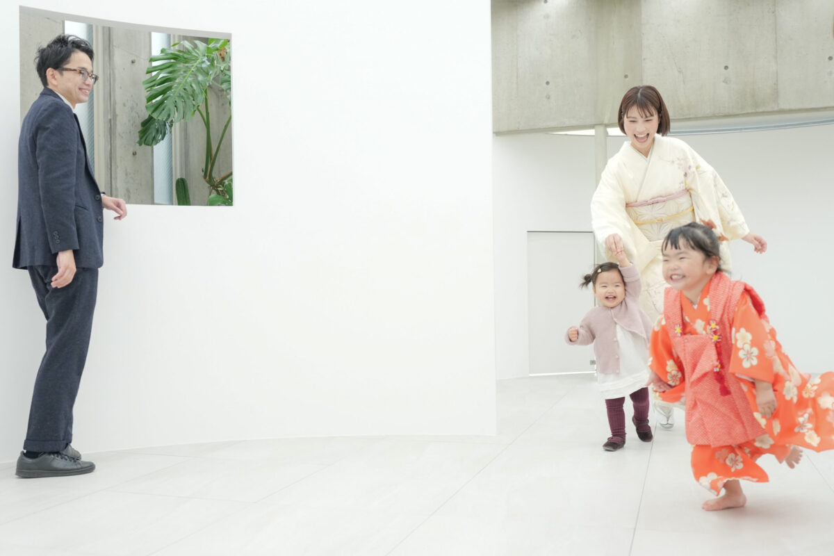 広島市安佐南区・十色写真STUDIOで3歳七五三の家族撮影。被布姿の女の子と妹が笑顔で駆け出す、明るく広いスタジオ空間