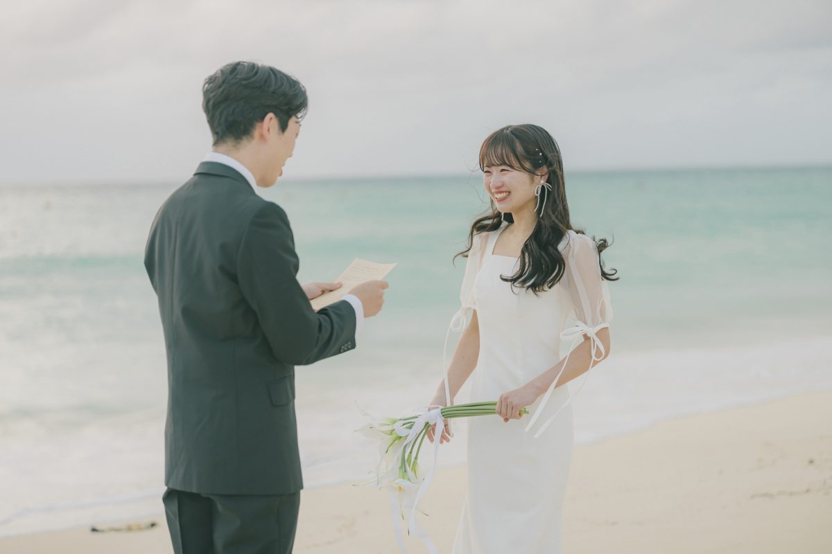 砂浜で手紙を読む新郎と笑顔で聞く新婦|宮古島のフォトウェディング・サプライズプロポーズ・十色写真STUDIO