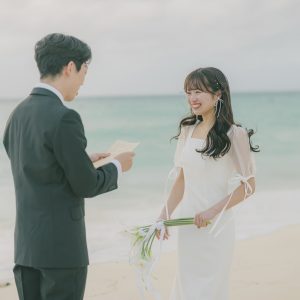 砂浜で手紙を読む新郎と笑顔で聞く新婦｜宮古島のフォトウェディング・サプライズプロポーズ・十色写真STUDIO