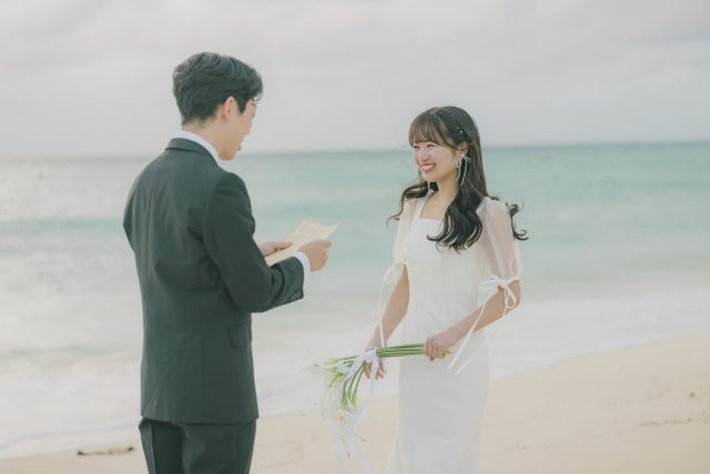砂浜で手紙を読む新郎と笑顔で聞く新婦｜宮古島のフォトウェディング・サプライズプロポーズ・十色写真STUDIO