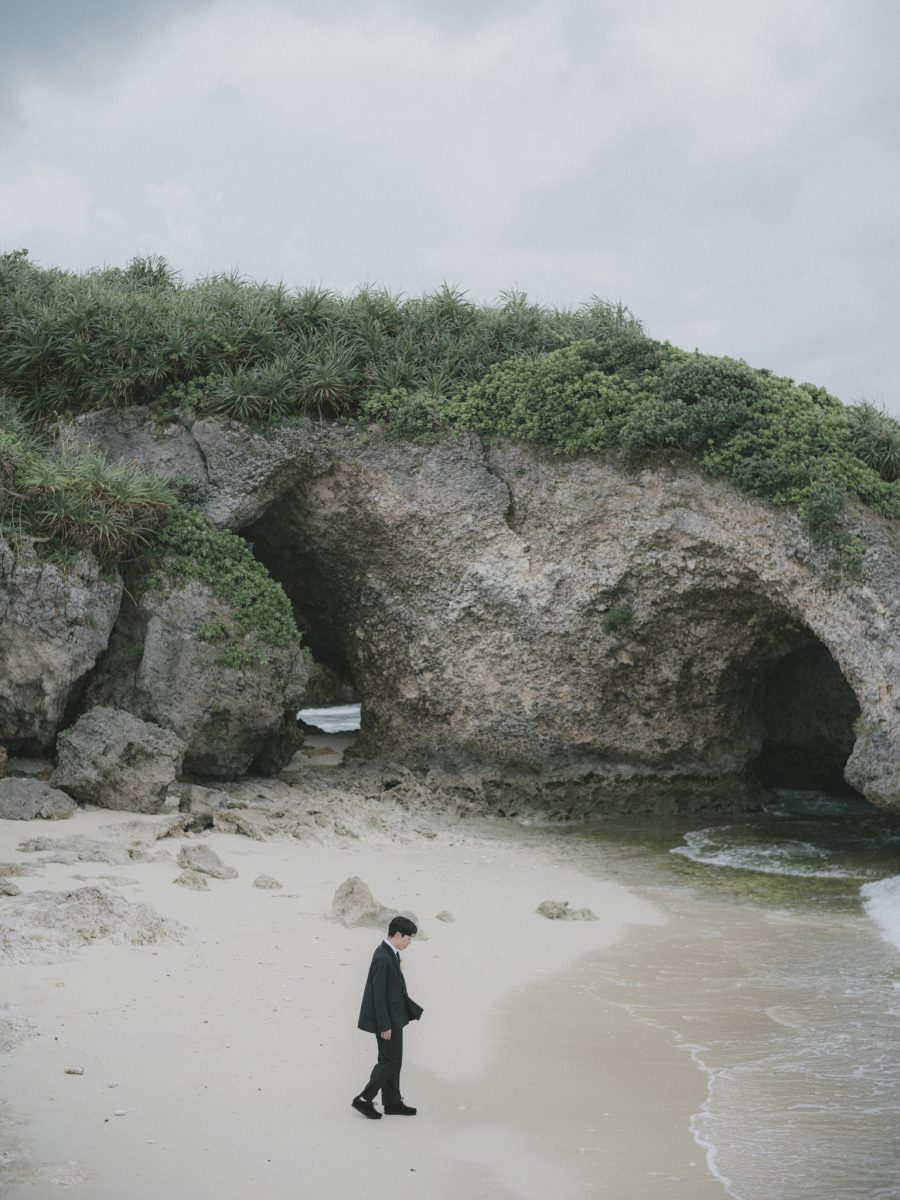 岩のトンネルがある海岸を歩く新郎|宮古島のフォトウェディング・十色写真STUDIO